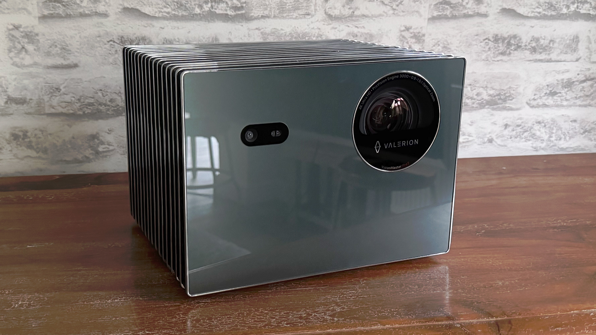 Valerion VisionMaster Pro 2 home cinema projector on wooden sideboard in front of white brick wall