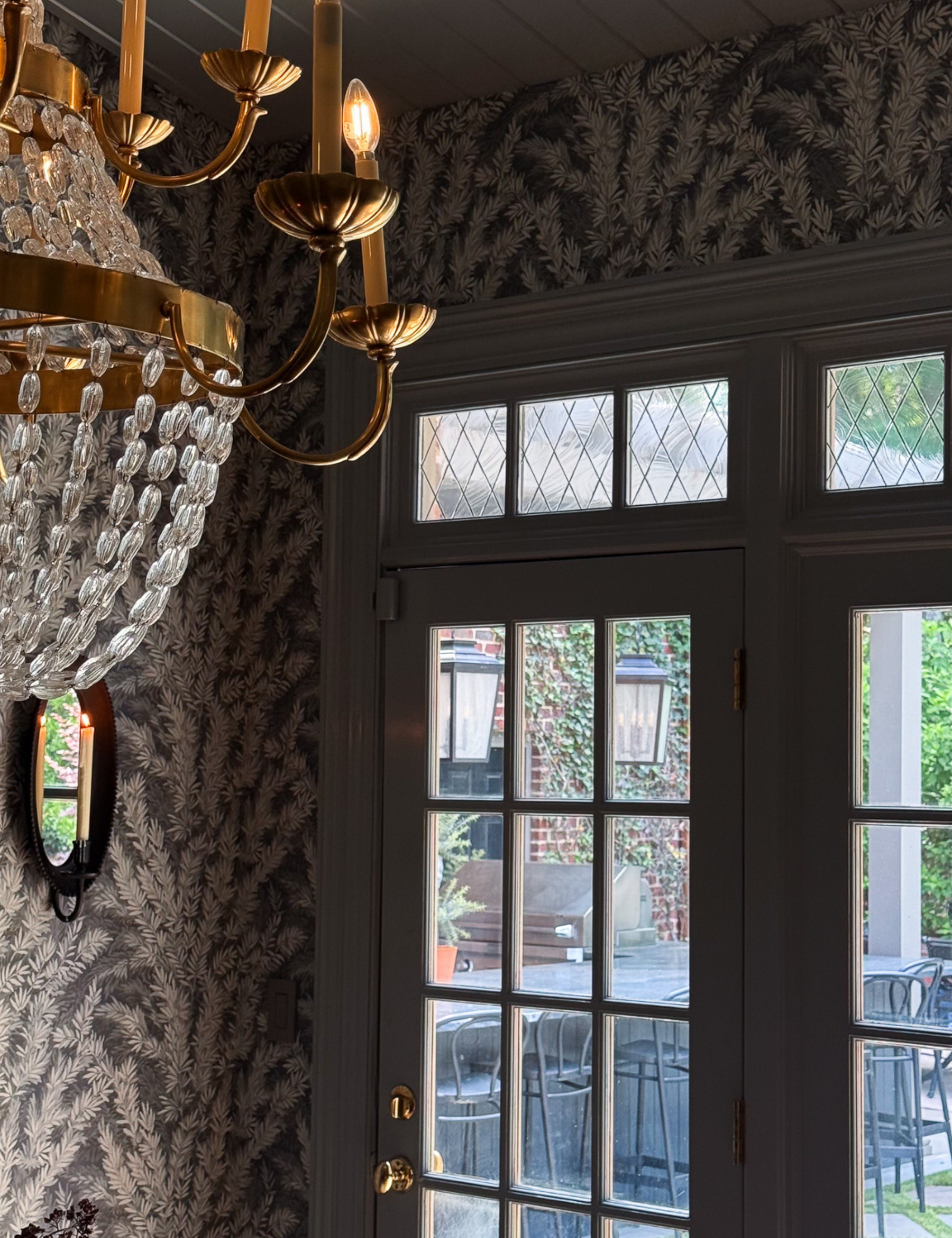 Dining room vignette featuring an ornate crystal-and-brass chandelier overlooking a set of windowpane doors, which are layered with peel-and-stick diamond grid window film at the top