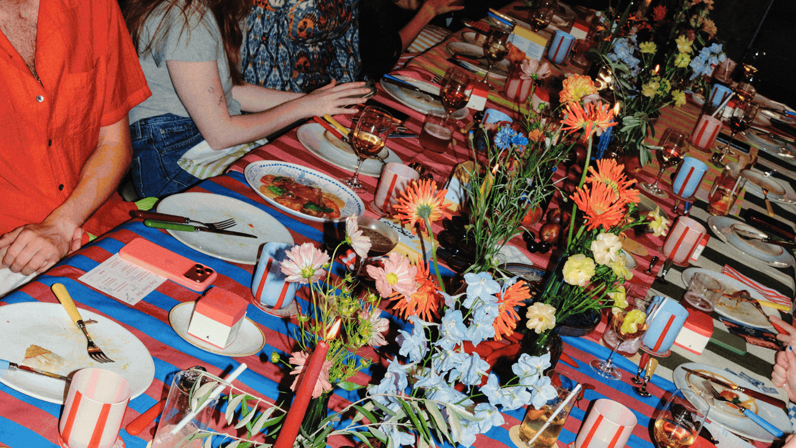 A rotating gif, showcasing a series of beautifully laid tables decorated with striped, colorful, and mismatched table cloths, along with colorful serveware and flowers, among others.