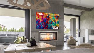 The TCL 6-Series wall-mounted above a fire in a living room.