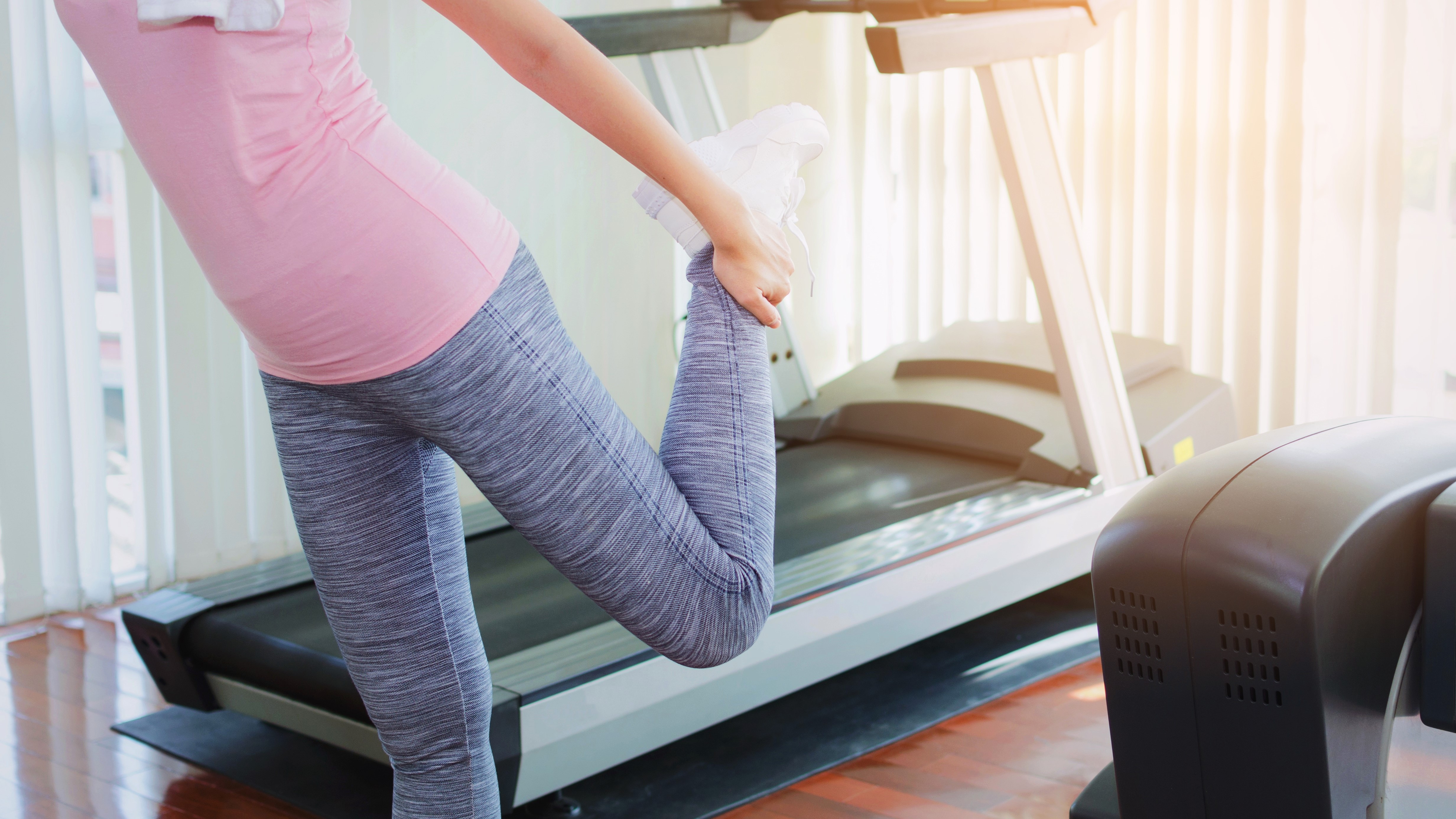 Woman stretching beside treadmill
