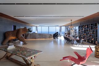 Giant gorilla sculpture, table and chairs and black wall shelves with view of the ocean out glass window