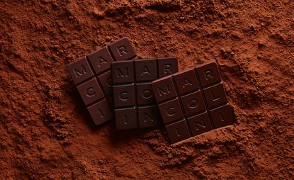 Pierre Marcolini Grand Cru square chocolate tablets with 'MARCOLINI' lettering surrounded by chocolate powder