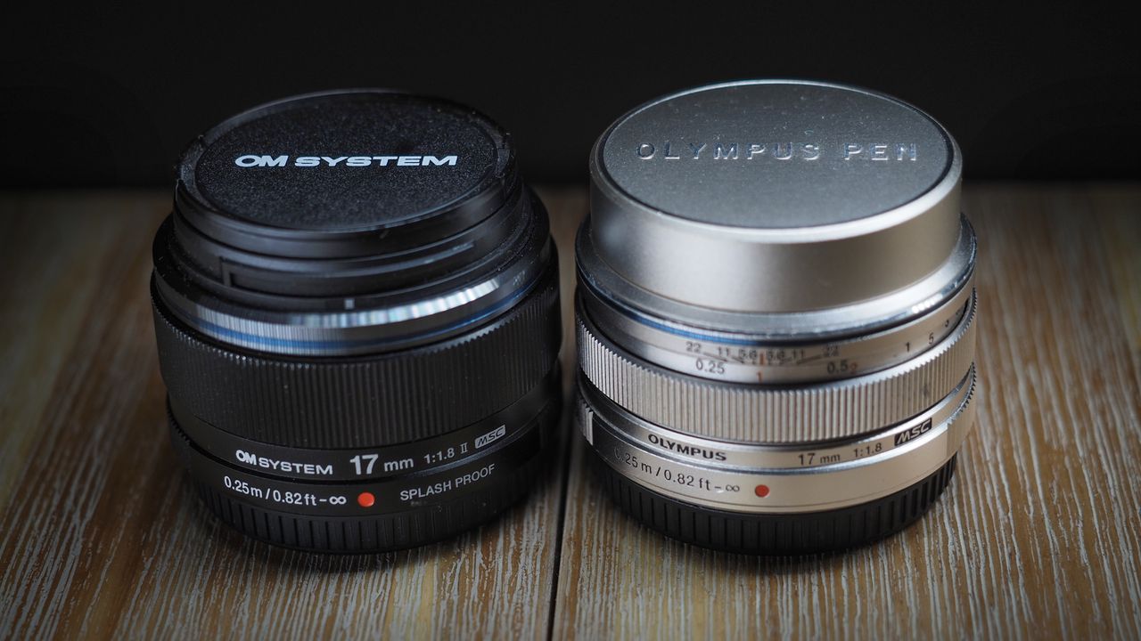 OM System M.Zuiko 17mm f/1.8 II next to an Olympus M.Zuiko 17mm lens on a wooden surface