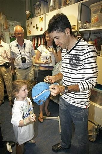 Carlos Sastre presents a hat to a young girl