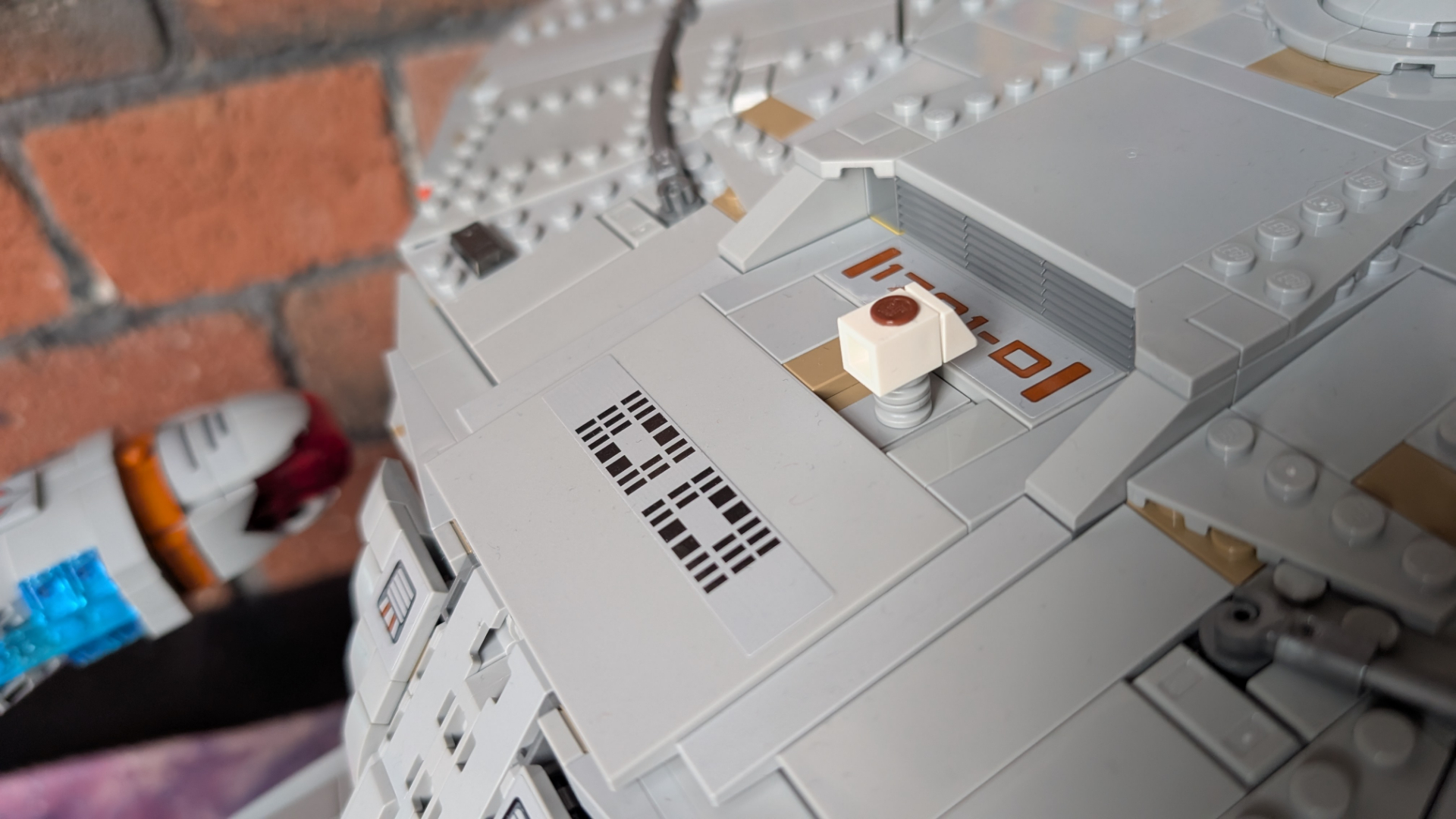 Lego U.S.S. Enterprise set on stand, with a close-up of a miniature shuttle entering the shuttle bay at the back of the saucer section