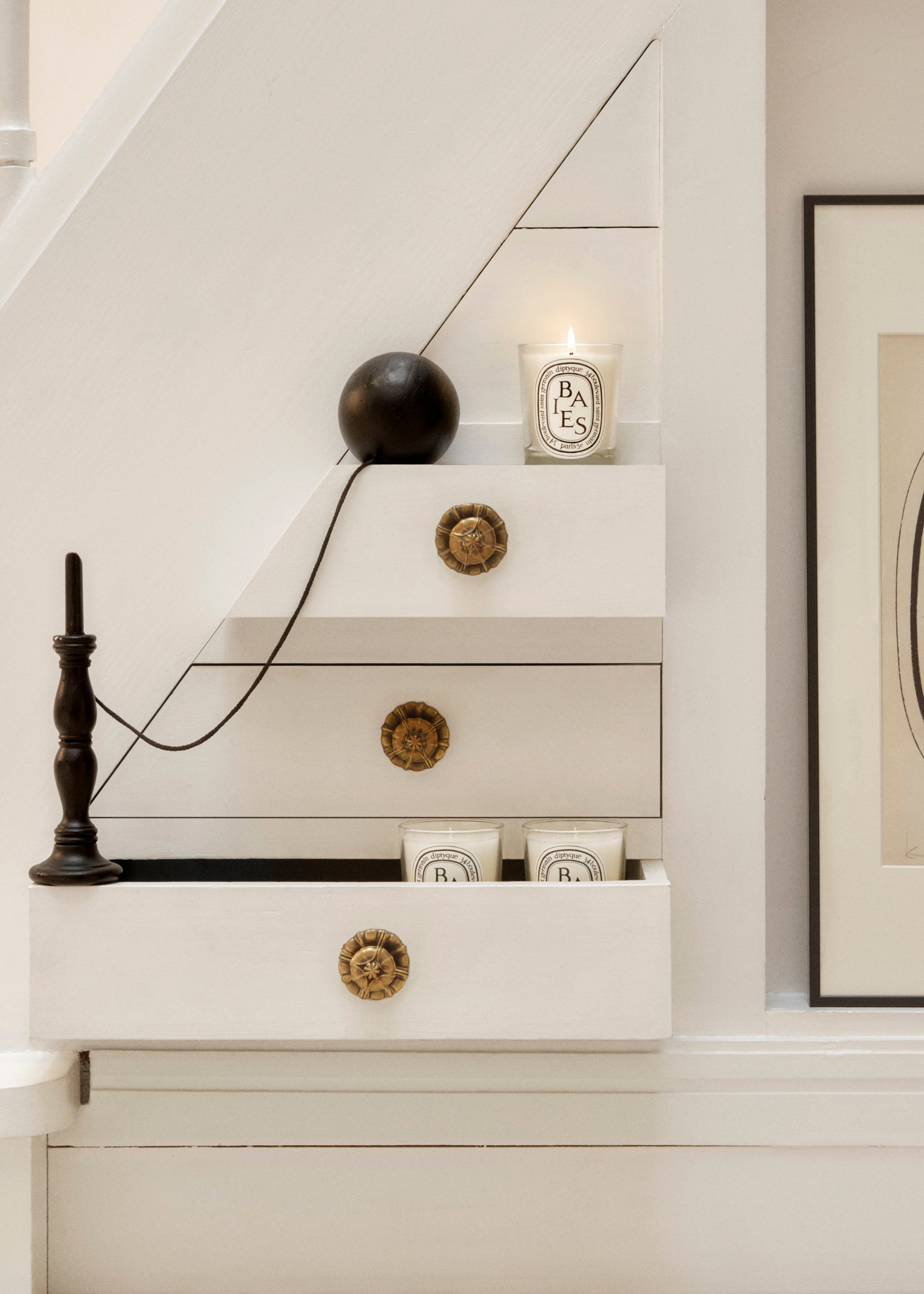 A set of white drawers with Diptyque candles on the front