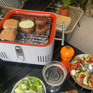 The Cube BBQ in action with burgers and buns cooking, salads on the side