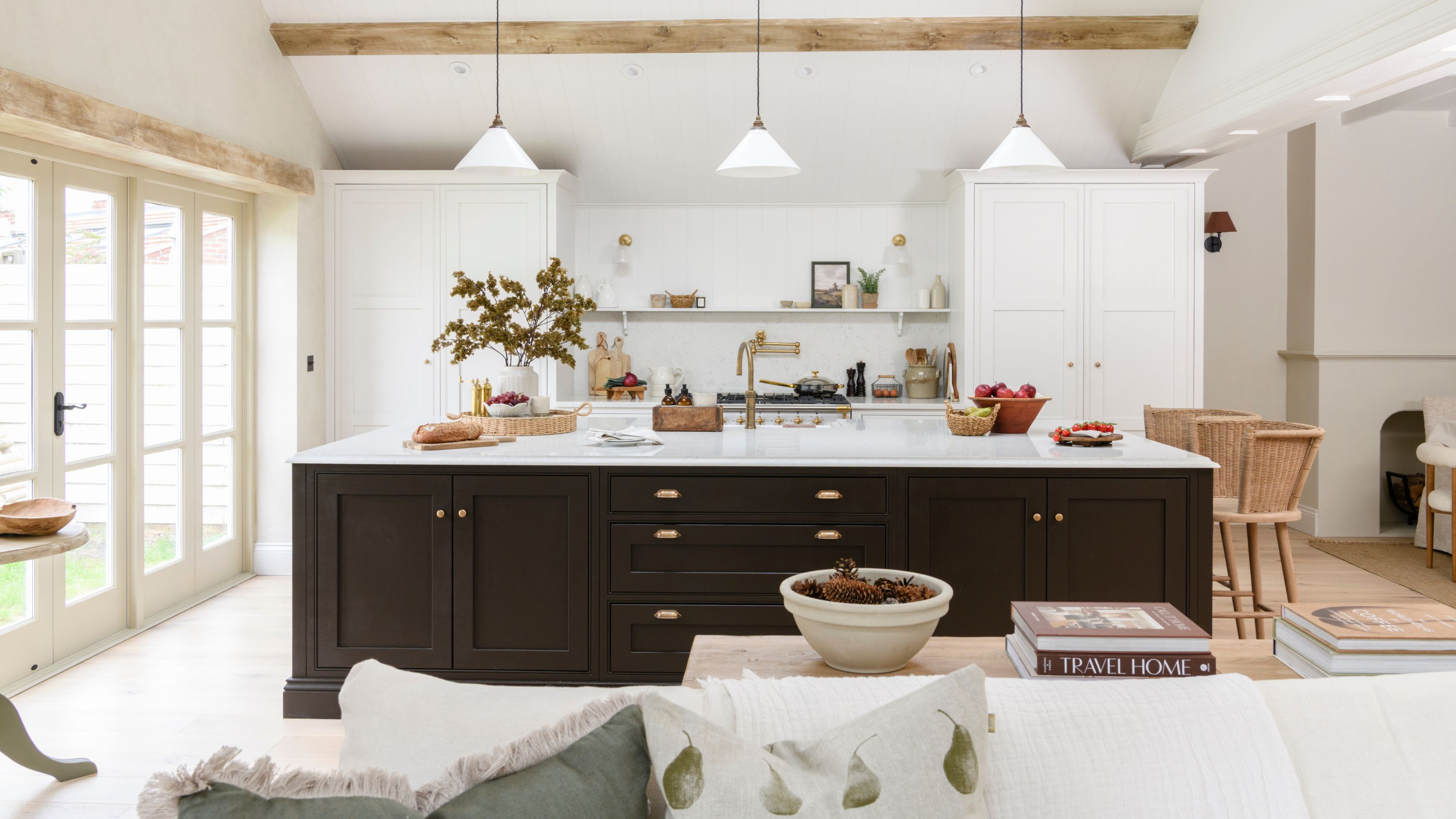 White kitchen with white cabinets at the back and a large island with black cabinets and white worktop in the middle of the room