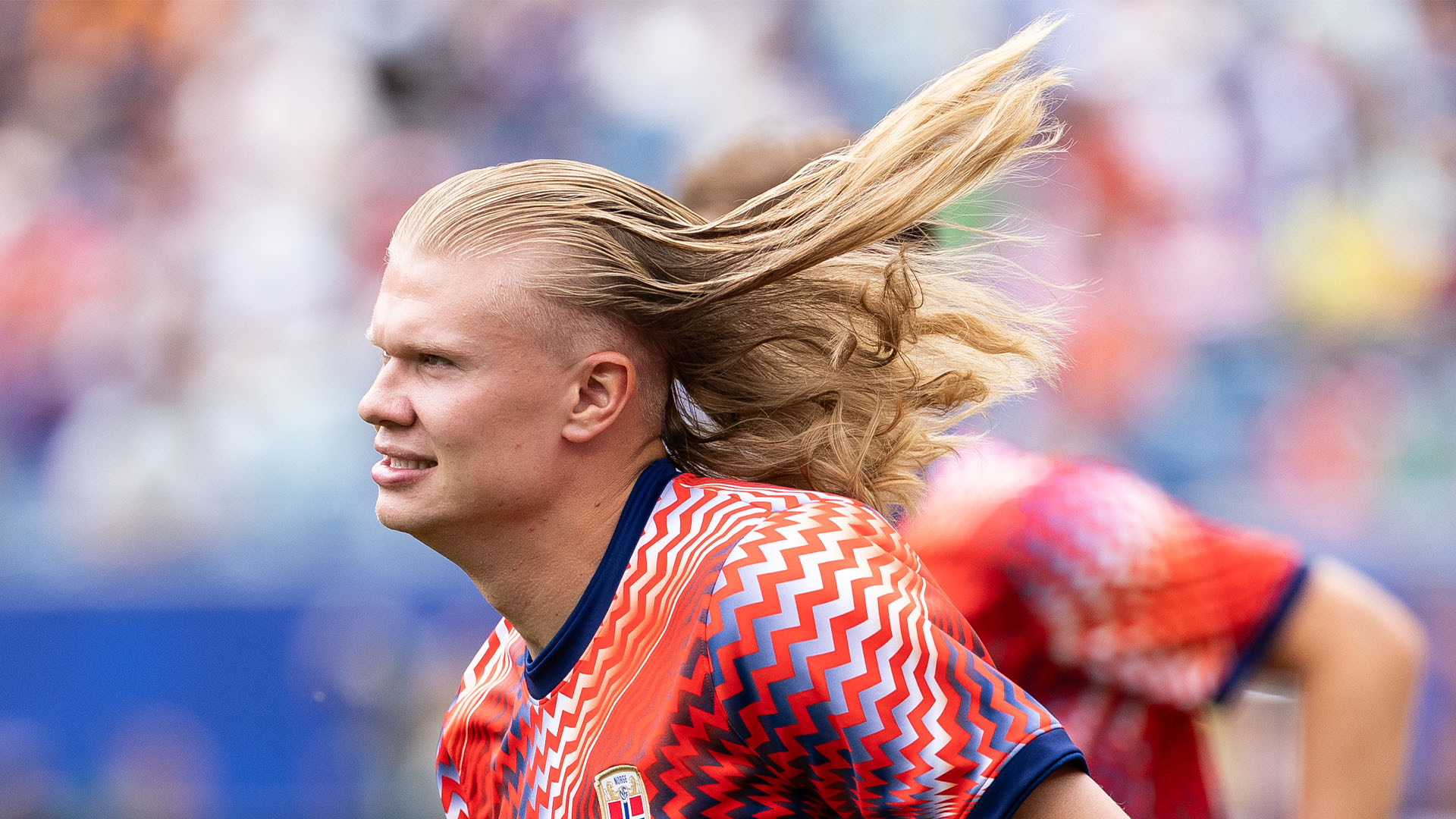 Erling Haaland on the pitch with his hair flowing behind him 