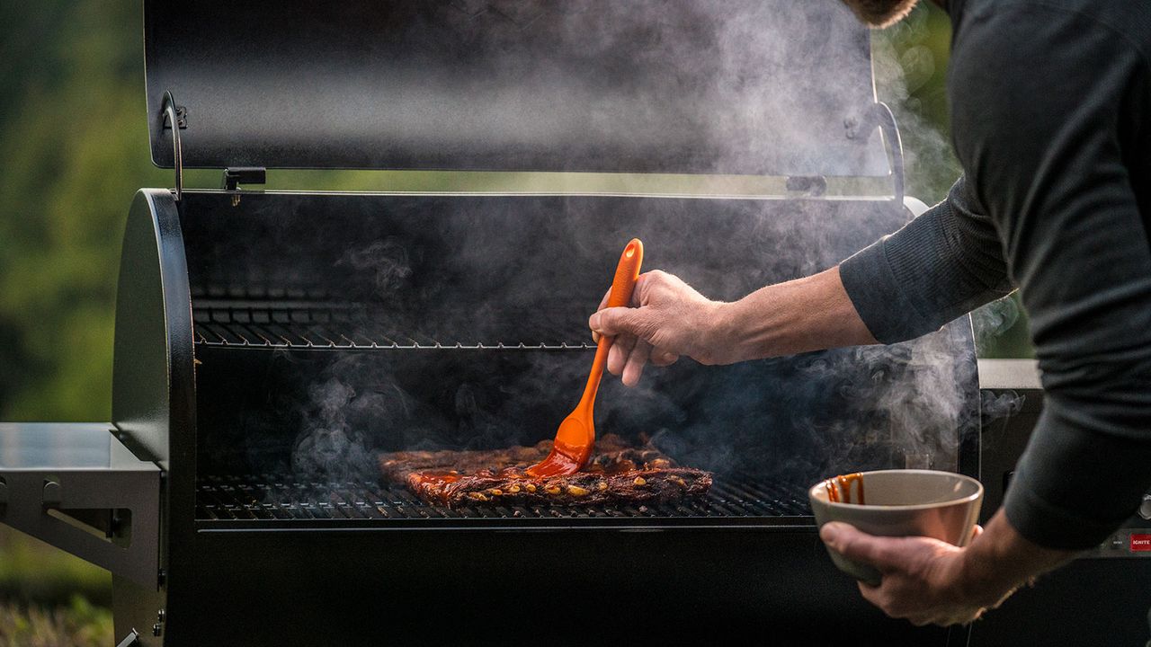 person cooking on a wood pellet smoker grill