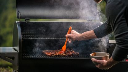 person cooking on a wood pellet smoker grill