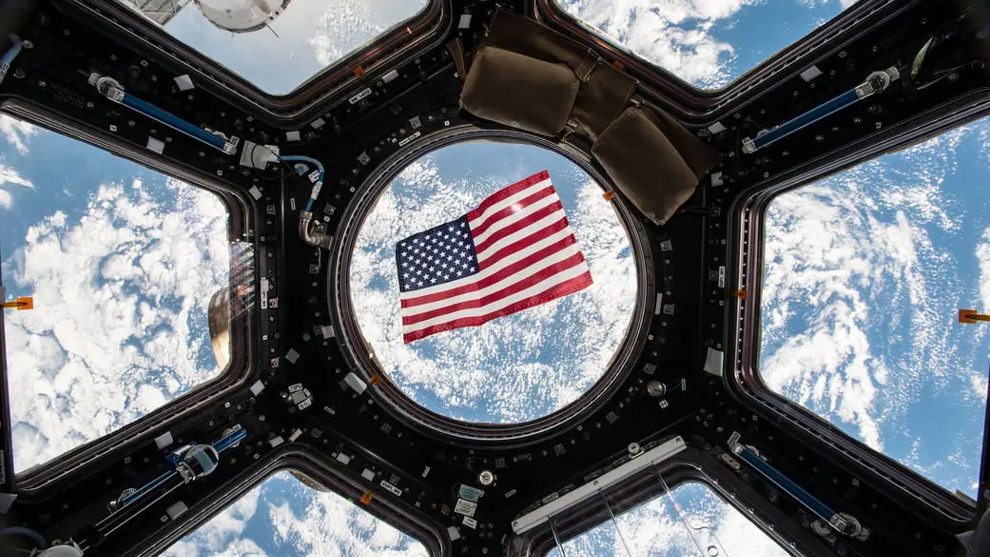 an american flag against a round glass window through which earth can be seen from space