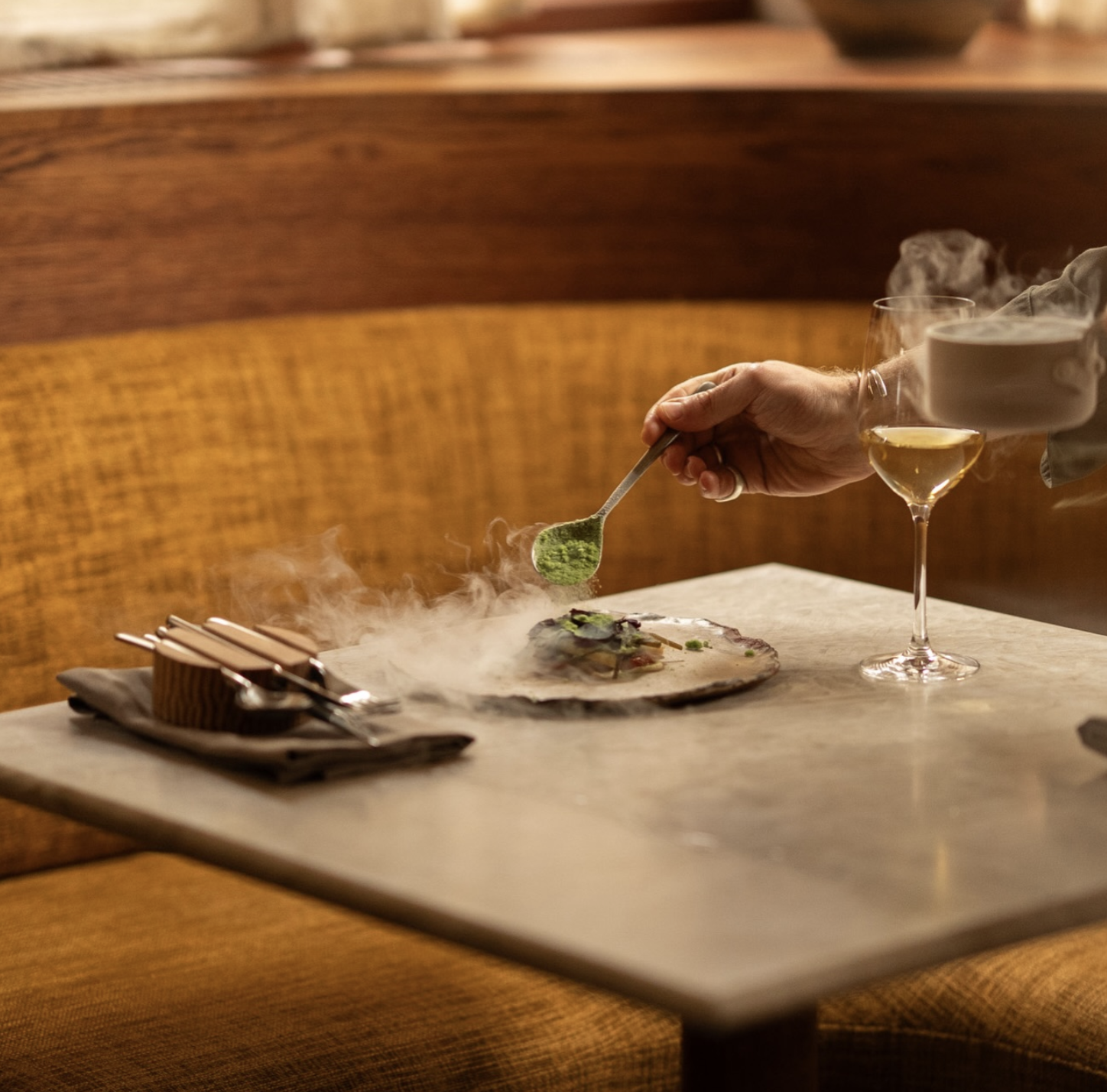 an image of a dish being plated on a table, with smoke and steam around it