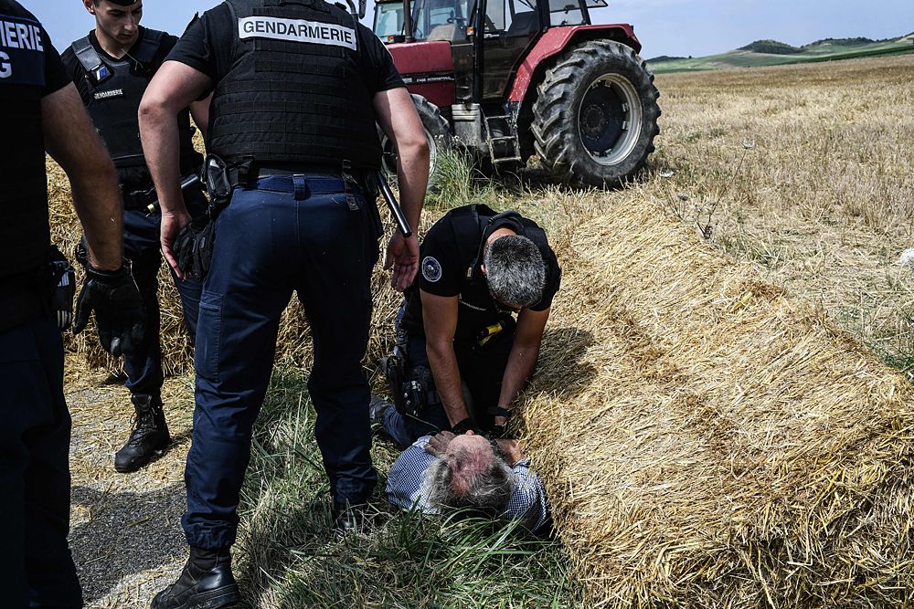 Gendarmes detain a protester during a farmers' protest who attempted to block the stage's route, during the 16th stage of the 105th edition of the Tour de France