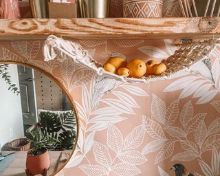 A macrame hanging fruit hammock in kitchen with coral-colored wallpaper covering