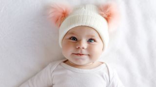 Baby wearing a warm white and pink hat with cute bobbles