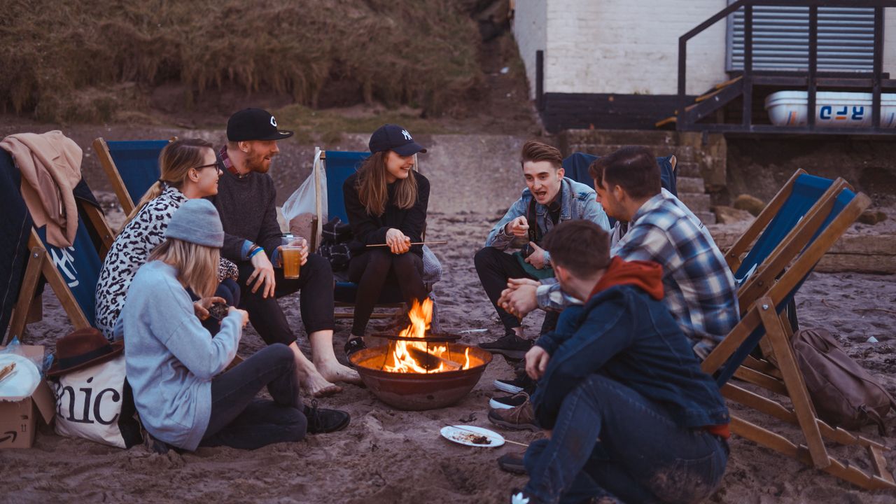 People sitting around beach fire pit