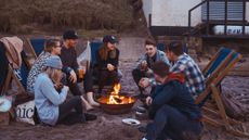 People sitting around beach fire pit