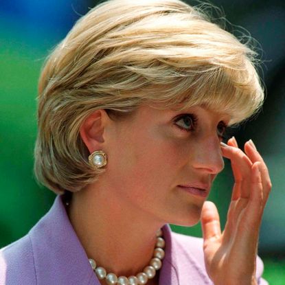 Princess Diana wearing a lavender suit and wiping her eye