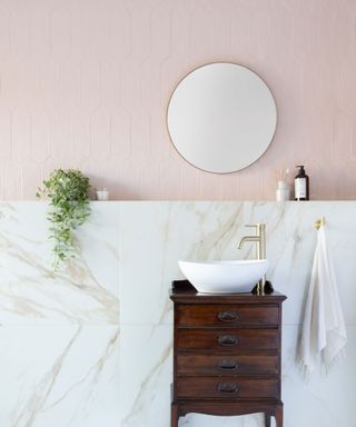Bathroom sink area with light pink wall tiles and marble wall tiles