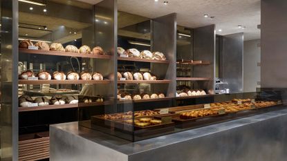 The Bakery in Ghent with loaves of bread lined up on the wall of chrome interior cafe