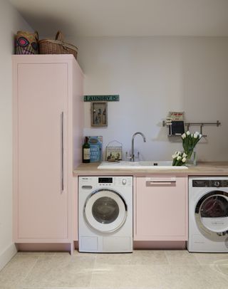 pastel pink laundry room with painted units washing machine and dryer