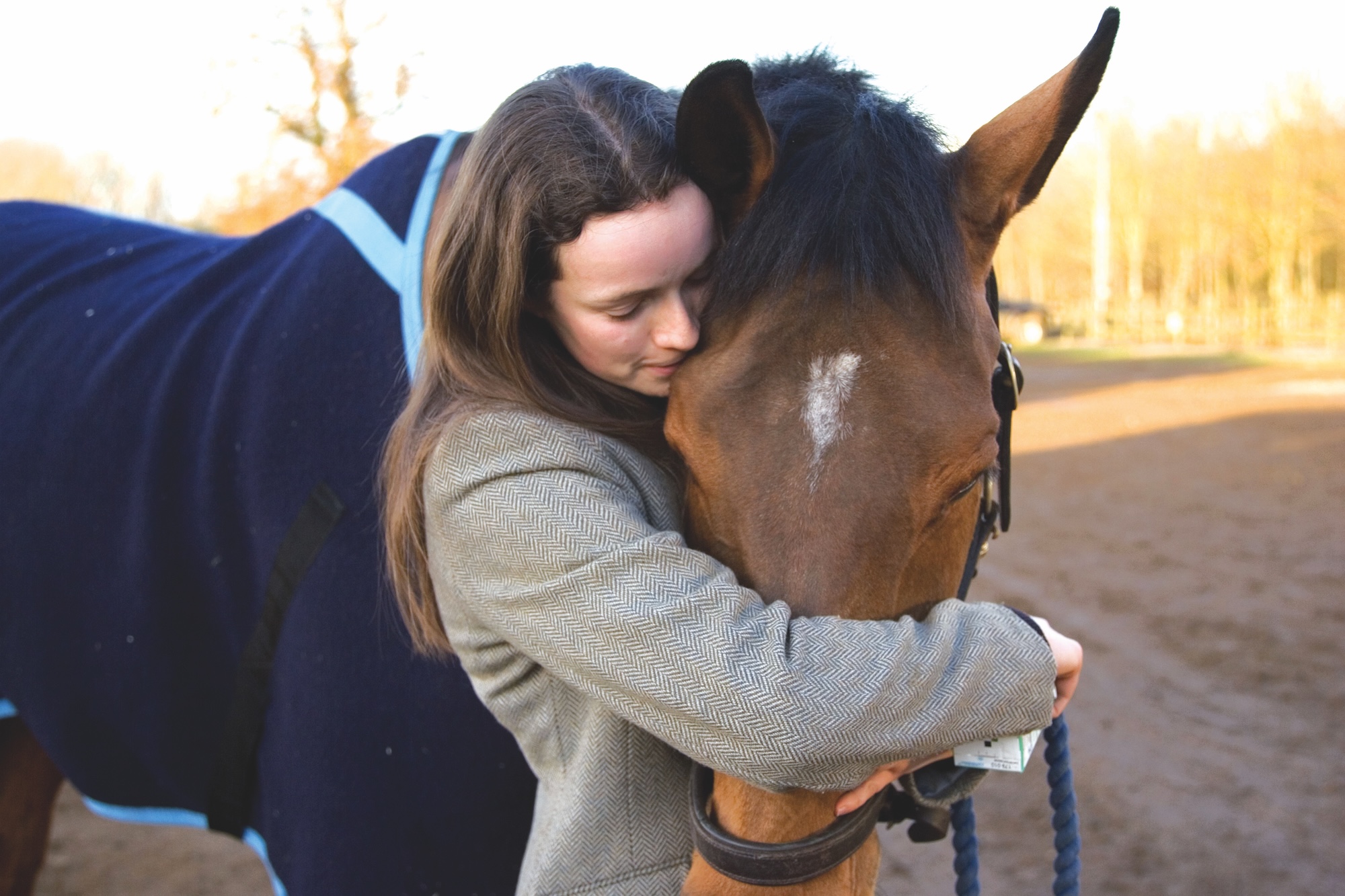 A rider holding and hugging her horse