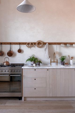 A sleek kitchen with pots and other items hanging above the cooktop