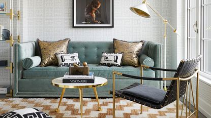 Jonathan Adler blue sleeper sofa in living room, decorated with cushions, floor lamp, chairs, rug, artwork on walls