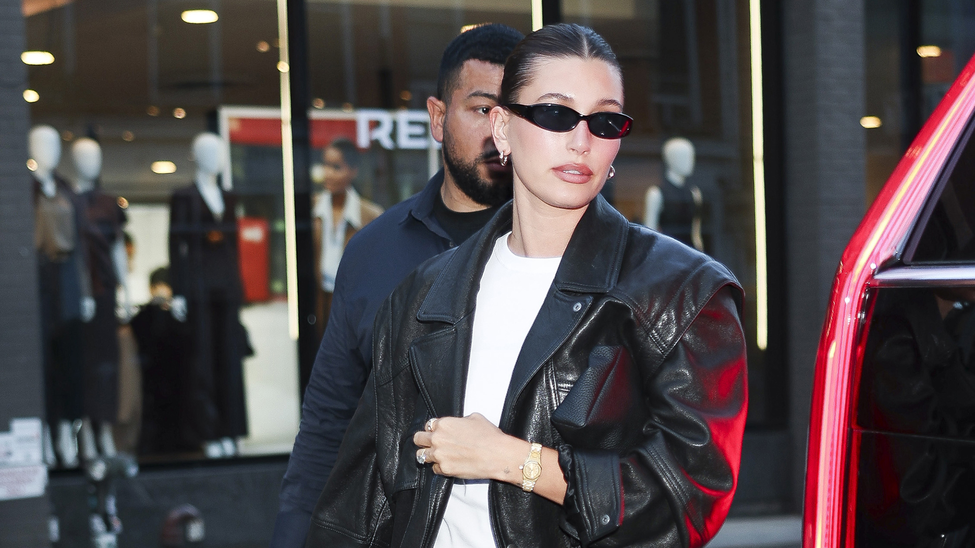 Hailey Bieber wearing a leather bomber jacket, white T-shirt, and athletic shorts in NYC
