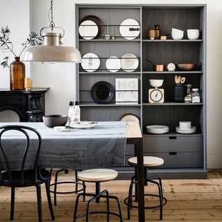 A dining room with a grey sliding door display cabinet, wooden flooring and a pendant light