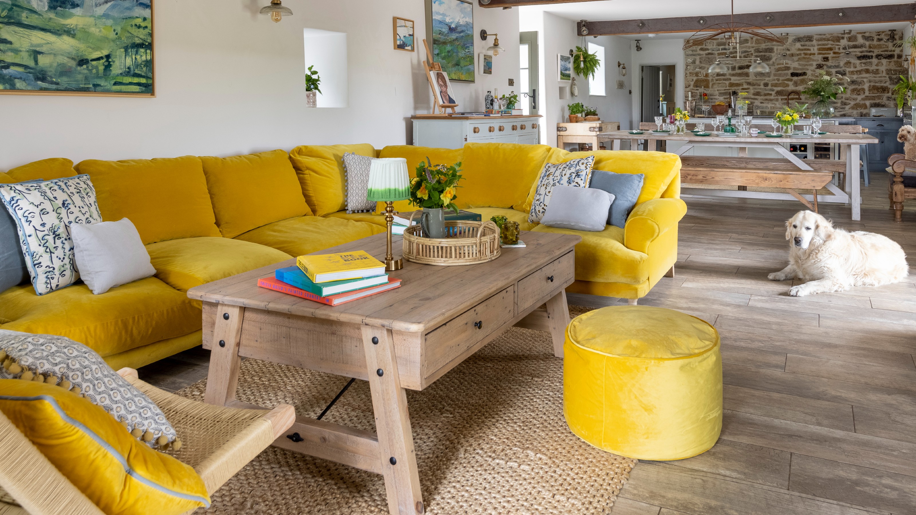 An open-plan living room with a corner bright yellow sofa with a wooden storage rectangular coffee table on a jute rug