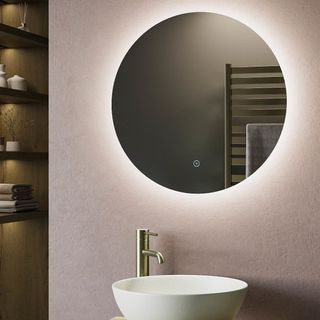 round backlit mirror on pink wall with round basin and gold tap underneath