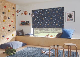 Child's bedroom with plywood climbing wall and space themed blinds next to bed
