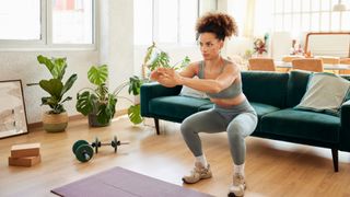 A woman doing a bodyweight squat in her living room