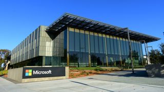 A front view of Microsoft's office in Washington showing a glass front building and a small sign with the Microsoft logo