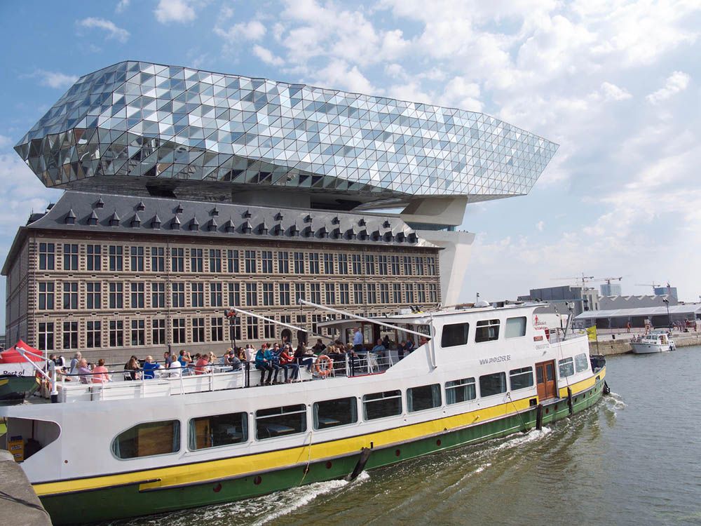 A river ferry cruises past the Havenhuis.