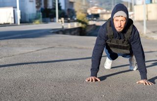 Man performing a push up wearing a weighted vest during workout outdoors