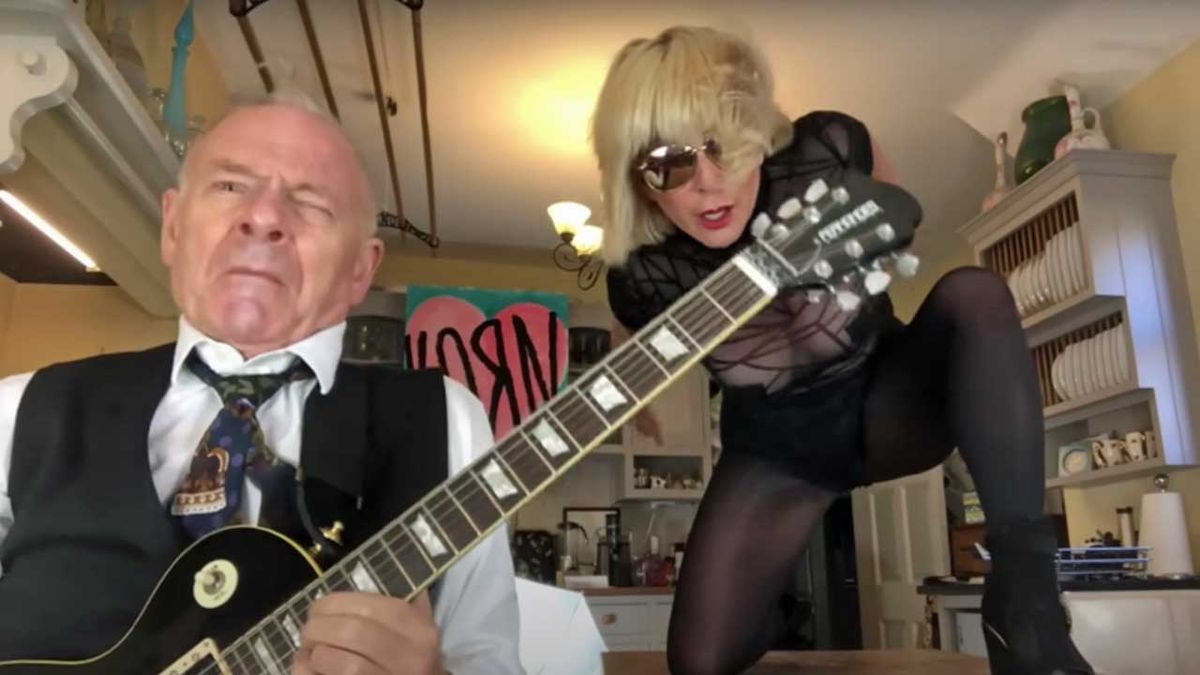 Toyah and Robert in their kitchen. Robert plays guitar, while Toyah clambers into the kitchen table