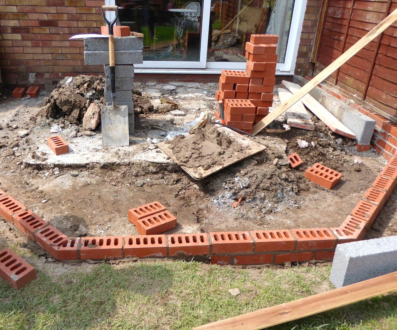 Red bricks being built in a hexagonal shape around a base ready to install a conservatory extension
