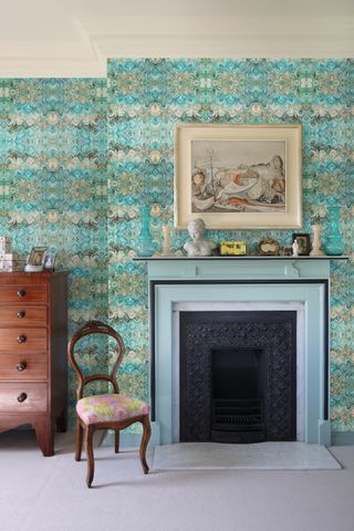 green and blue wallpaper in bedroom with fireplace and chair