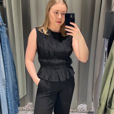 Woman in dressing room wears black top and black trousers
