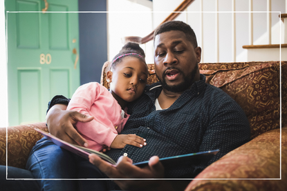 a dad reading a free book to his daughter on the sofa