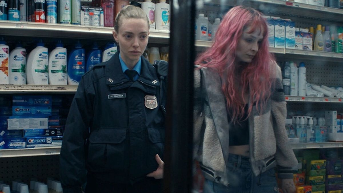 Police officer Mickey (Amanda Seyfried) somberly observes her pink-haired sister, Kacey (Ashleigh Cummings), as they stand side-by-side in a supermarket isle in Long Bright River.