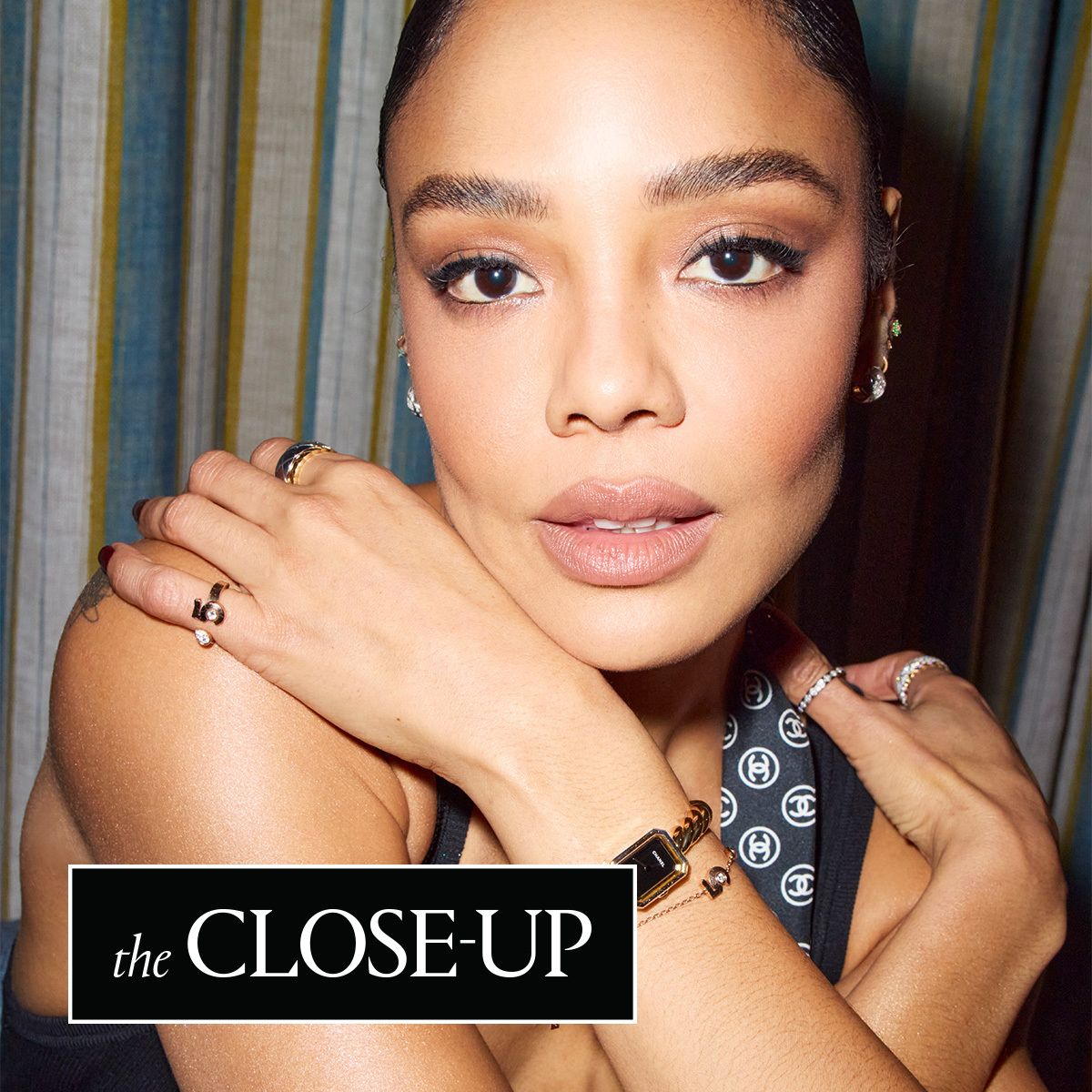 a close up of Tessa Thompson wearing a Chanel scarf and jewelry