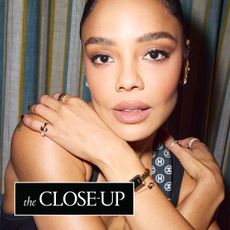 a close up of Tessa Thompson wearing a Chanel scarf and jewelry