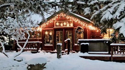 Christmas lights on wooden Colorado mountain country cabin in snow and pine trees