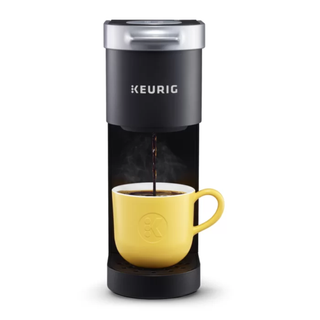 A Keurig K Mini Coffee maker filling a yellow Keurig-branded mug with black coffee