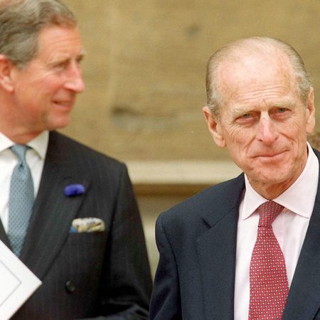 King Charles and Prince Philip pictured wearing suits and ties, with Philip smirking at the camera